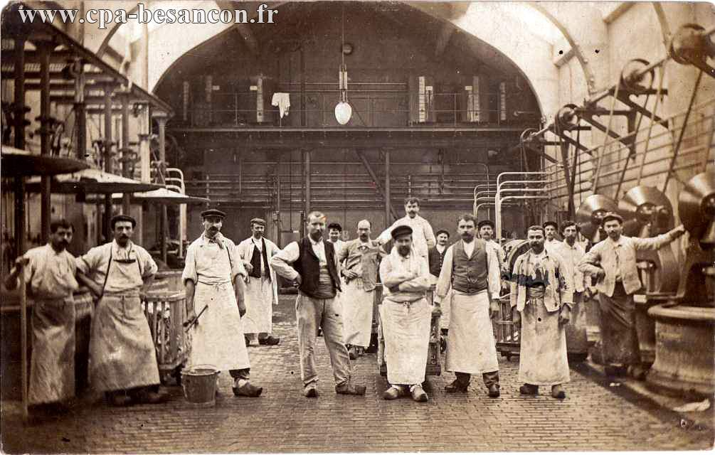 Un personnel en tablier à l'intérieur d'un vaste bâtiment d'usine.